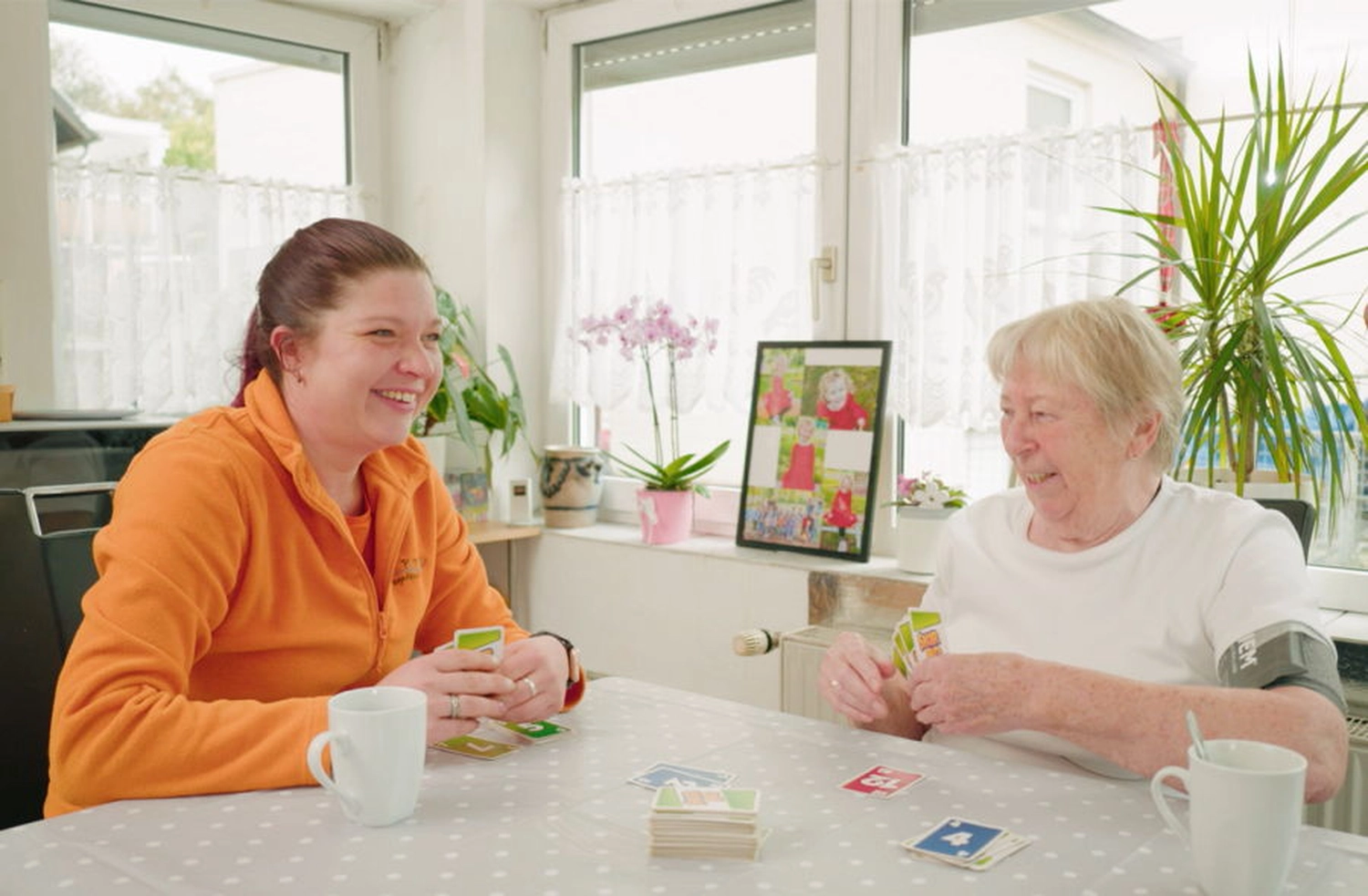 Zwei Pflegerinnen in der orangen Arbeitskleidung des Pflegedienst papillon bei der Planung einer Krankenpflege.