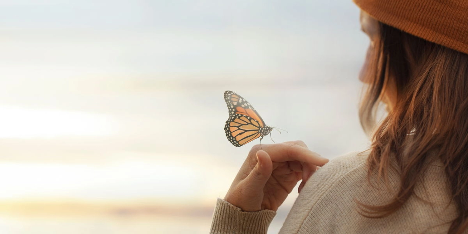 Einen junge Frau kit einem Schmetterling auf der Hand.